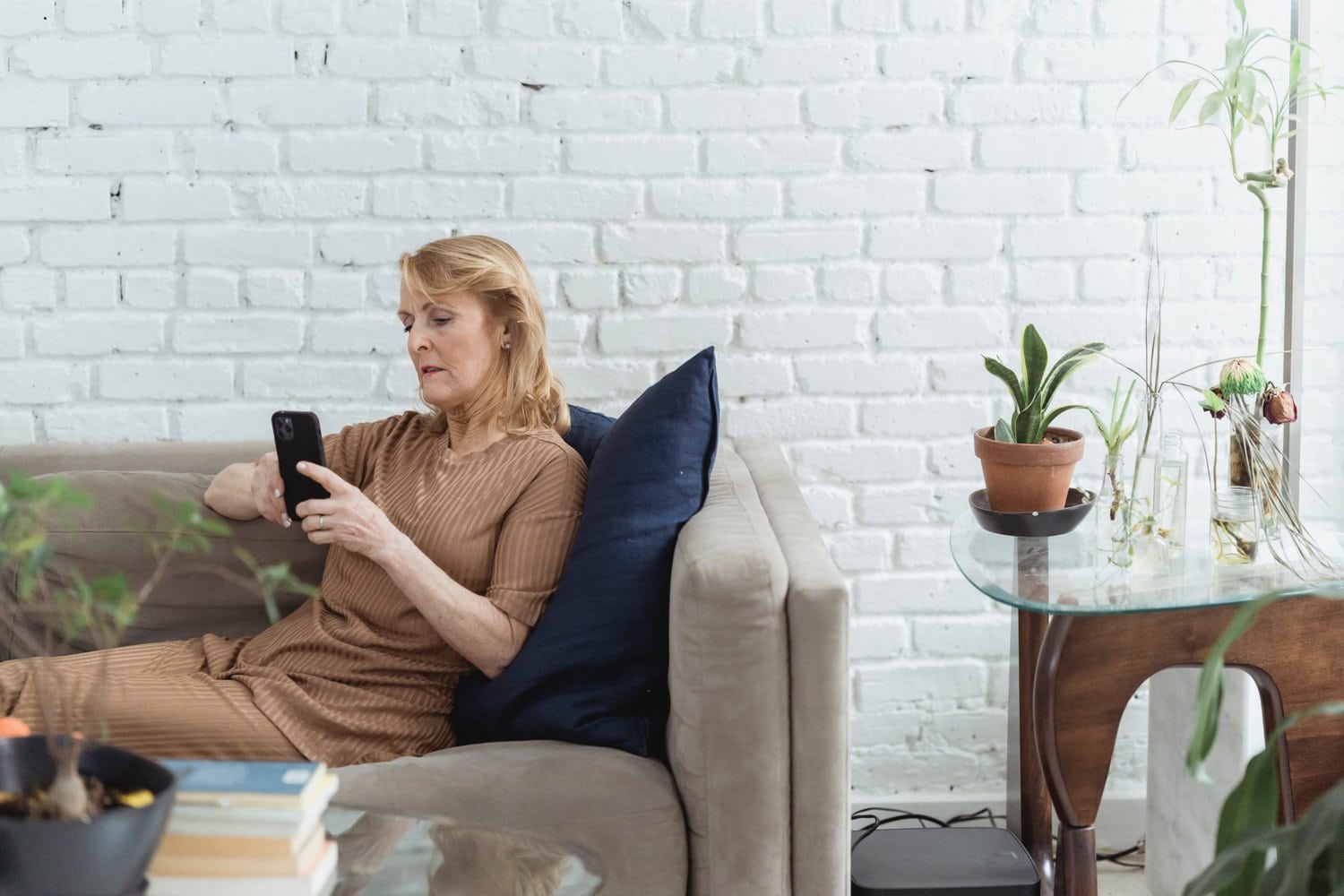 woman laying on sofa checking a smartphone