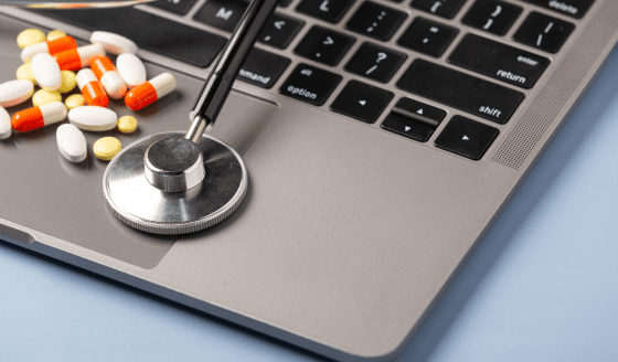 pills and stethoscope on a laptop