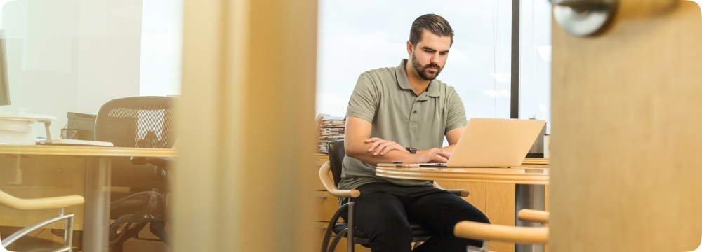 A main in a office works on a laptop